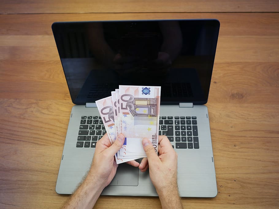 Hombre contando euros frente a su computadora